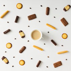 Coffee cup with cookies and coffee bean pattern on light background