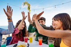 Diverse friends high-fiving at seaside cafe, celebrating outdoor fun