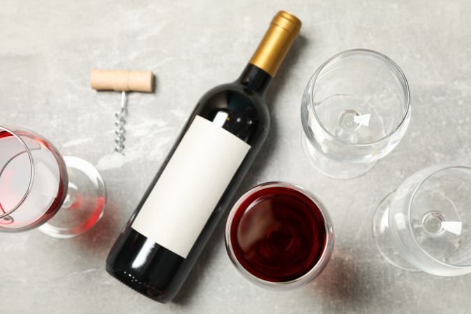 Flat lay composition with bottle and glasses of wine, corkscrew on grey background, copy space