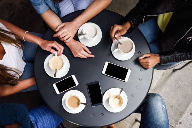 Shot of table of people with cappuccinos, lattes with smartphones