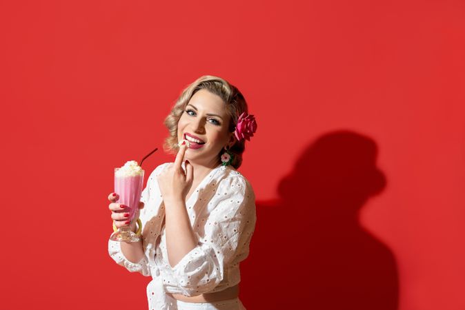Woman drinking a milkshake against a red background