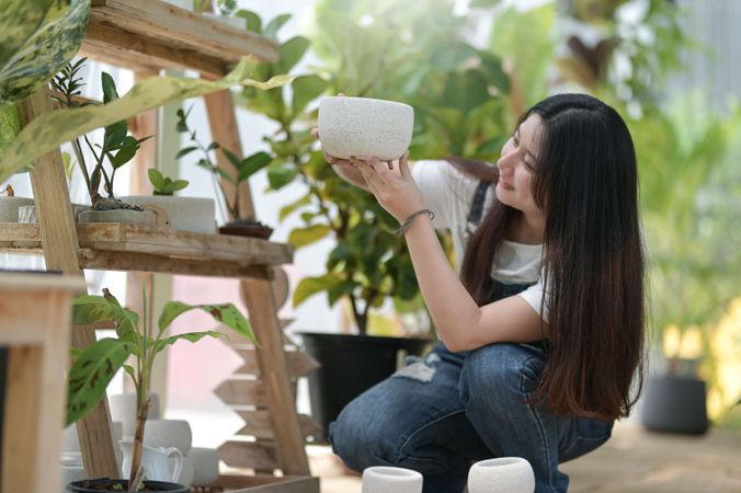 Asian female examining different sizes of plant pots at work
