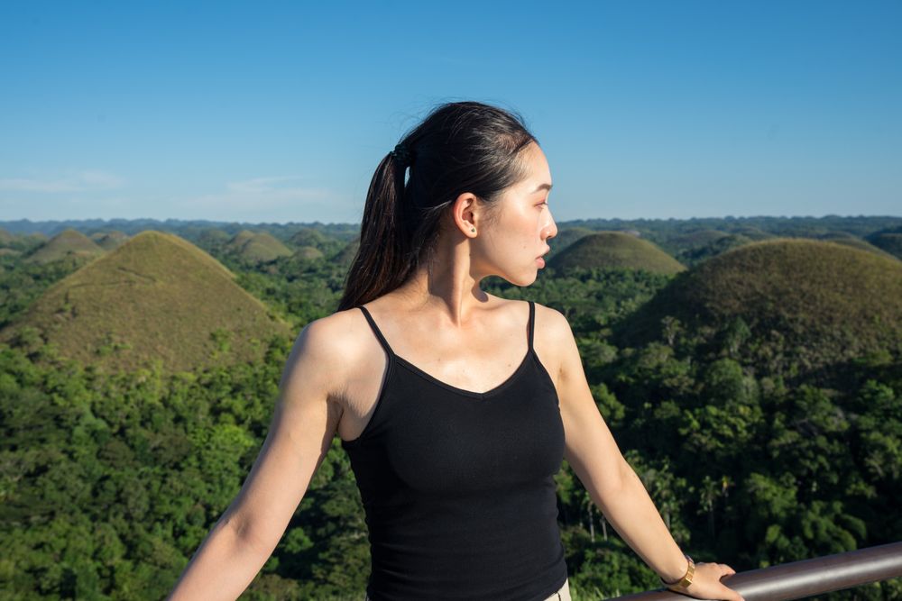 Happy woman standing on observation deck on hill