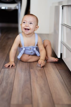 Happy baby sitting on floor in kitchen