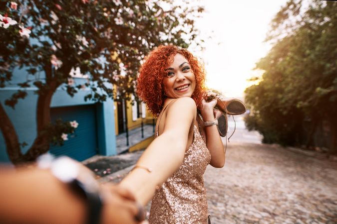Smiling young woman with golden brown curly hair having fun holding her partner's hand