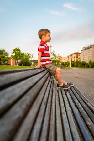 Boy sitting on the top of bench park relaxing