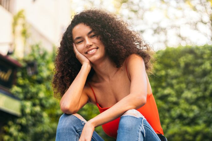 smiling young woman with curly hair portrait sitting on a stairs
