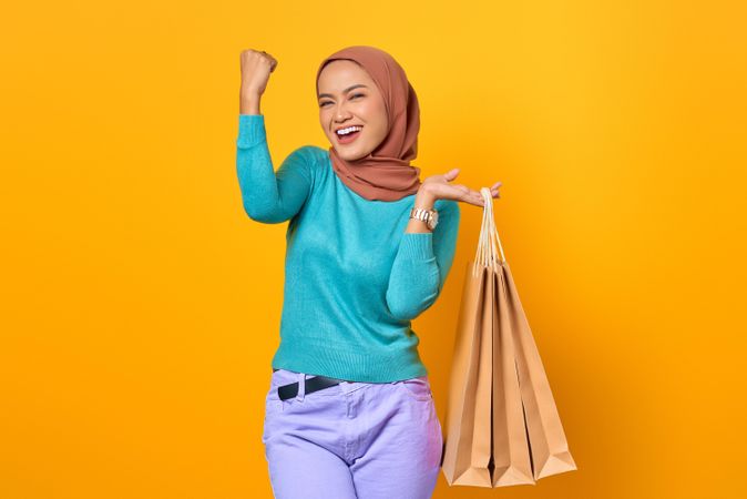 Muslim woman with shopping bags and hand up in victory