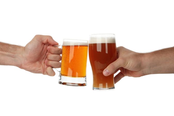 Hands hold glass of beer, isolated on light background