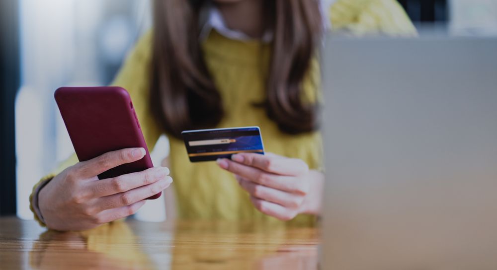 Young woman paying online by smartphone and credit card