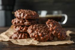 Chocolate cookies and cup of coffee on wooden table against dark background, space for text
