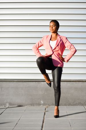 Female in modern business suit standing on one leg outside
