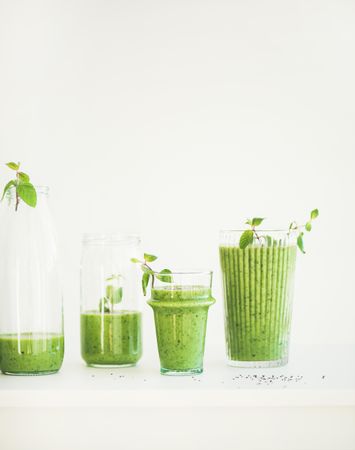 Green juice in bottles and jars garnished with mint leaf