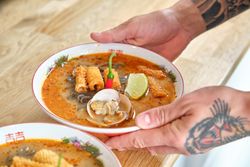 Man serving noodle soup on wooden table