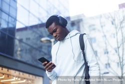 Young Black man standing in the street wearing headphones 4mWV1X