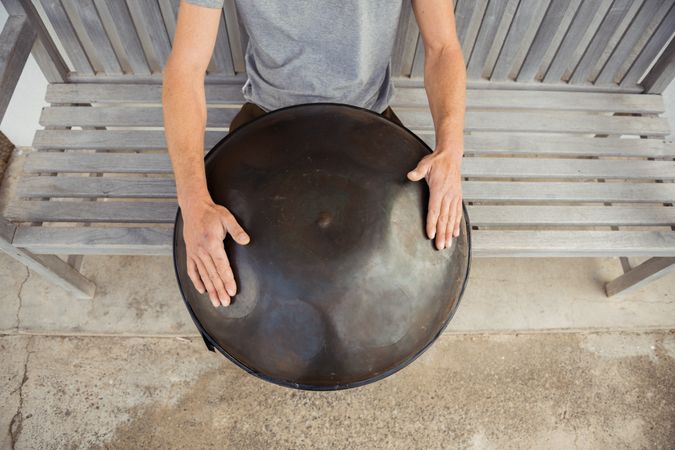 Blond man sitting on bench with big hand drum