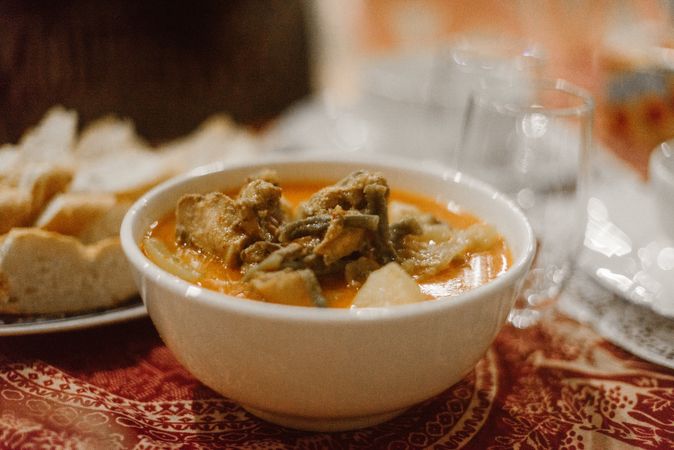 Bowl with soup and meat on table
