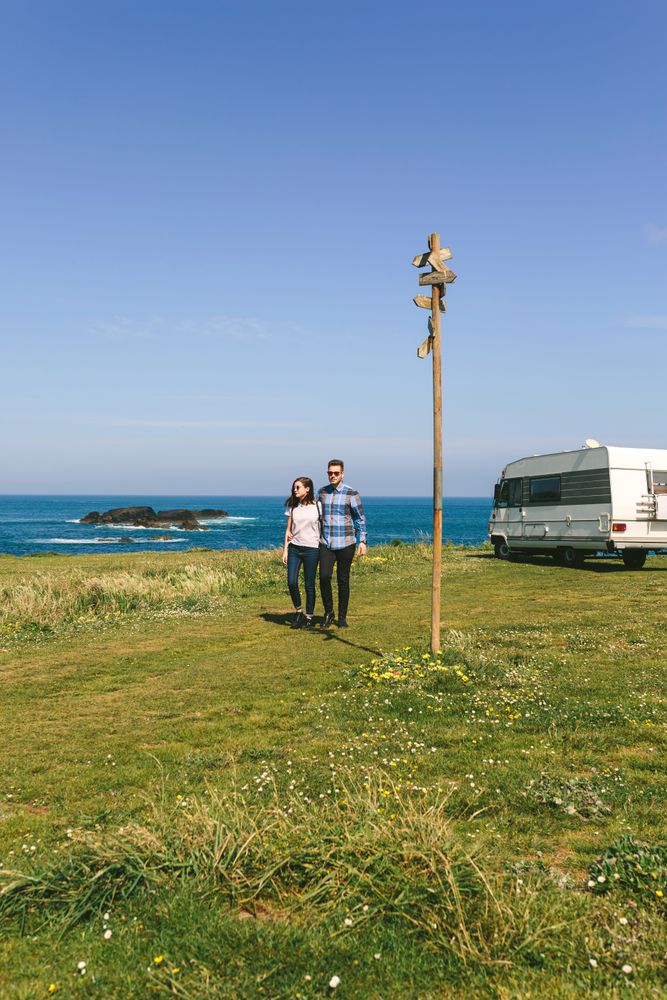 Couple taking a walk near the coast with a camper