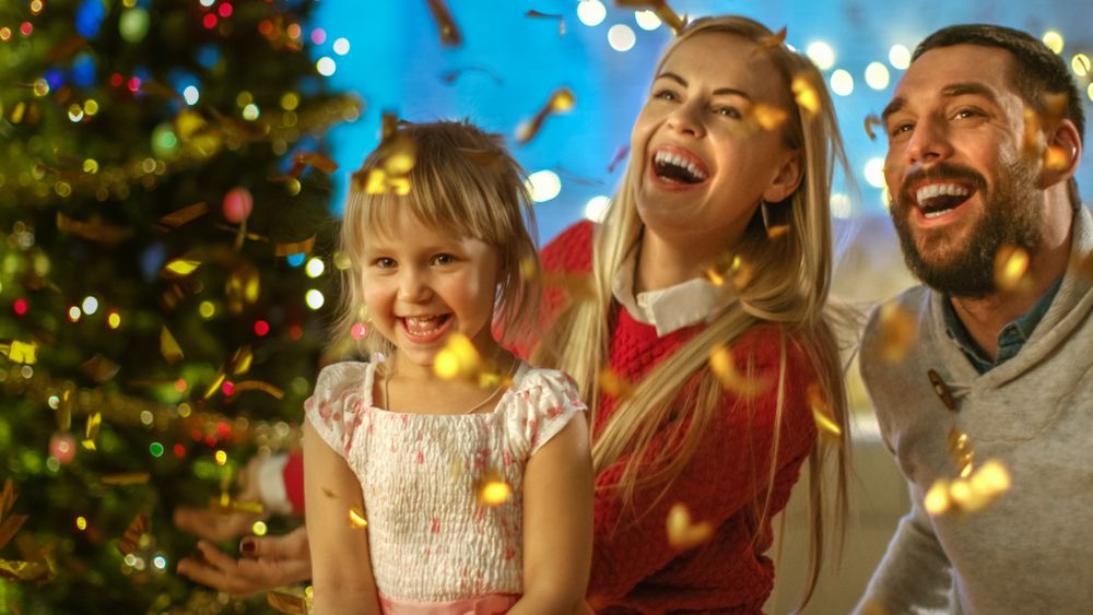 On Christmas Eve Father, Mother and Their Little Daughter Have Good Time Celebrating with Shooting Confetti.
