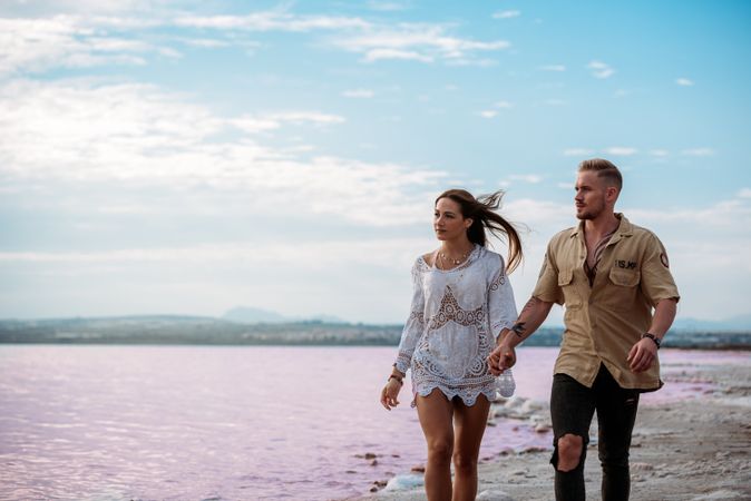 adorable couple walking on an amazing beach with pink water