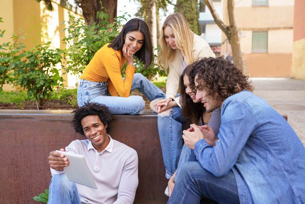 Multi-ethnic friends watching something on a digital tablet outside