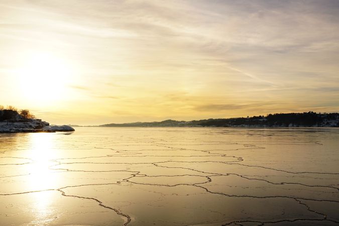 Breaking ice at scenic frozen river at sunset