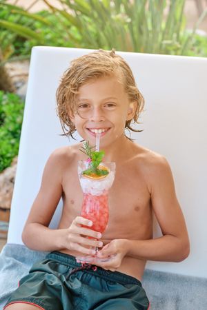 Cheerful boy with cocktail glass smiling at camera