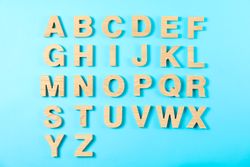 Wooden letters of English alphabet on color background, top view
