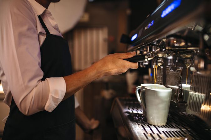 Cropped shot of barista using a coffee maker to prepare a cup of coffee