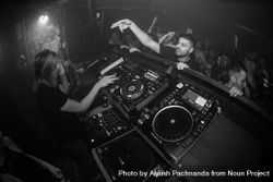 Fisheye shot of man reaching up into DJ booth as female DJ plays at nightclub 56GOP4