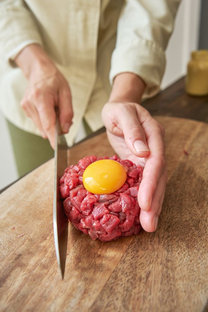 Faceless woman preparing delicious steak tartare for dinner at h