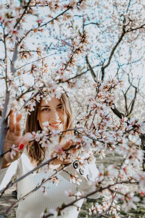 Young happy woman between trees in garden