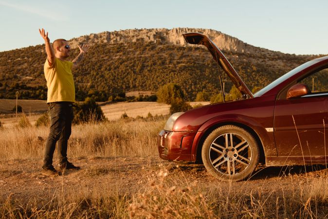 Annoyed man near broken car in countryside