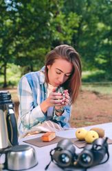 Woman holding cup of hot coffee sitting under blanket