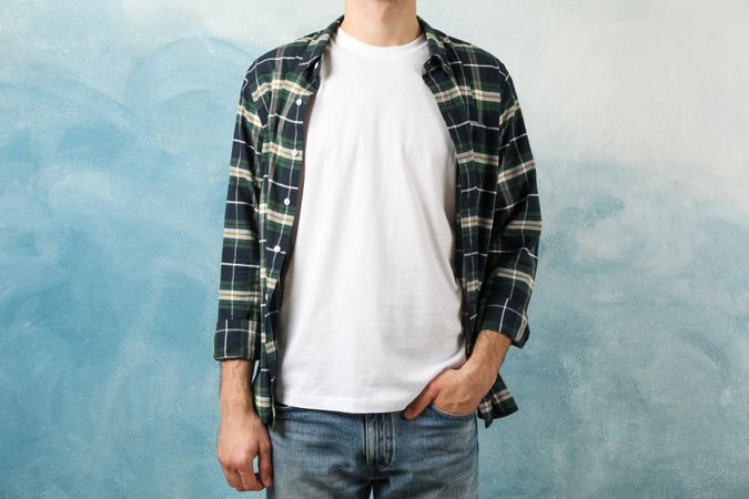Men in t-shirt and checkered shirt against blue background, copy space