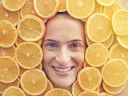 Smiling woman among slices of ripe oranges