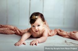 Baby girl on floor beside pink textile 0VGDr5