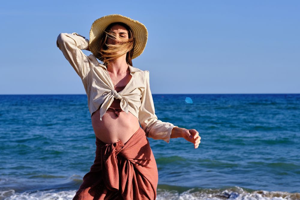 A fashion model with a hat at the beach before sunset