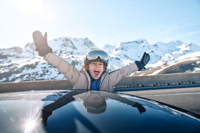 Excited boy leaning out of car window during ride on winter day