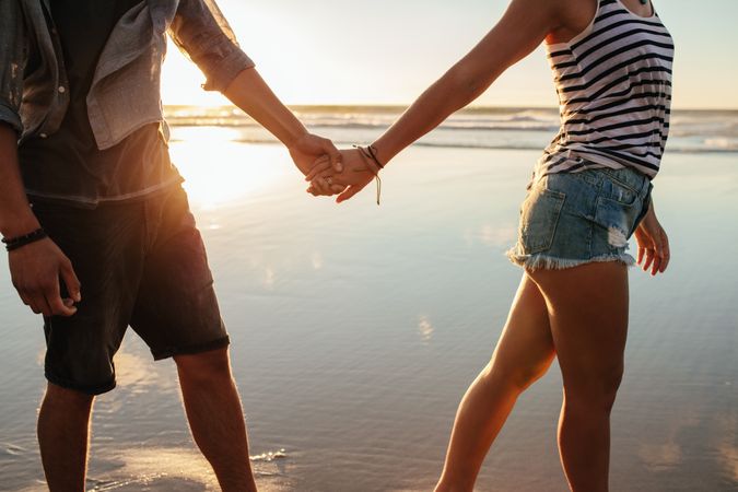 Fit couple holding hands along beach