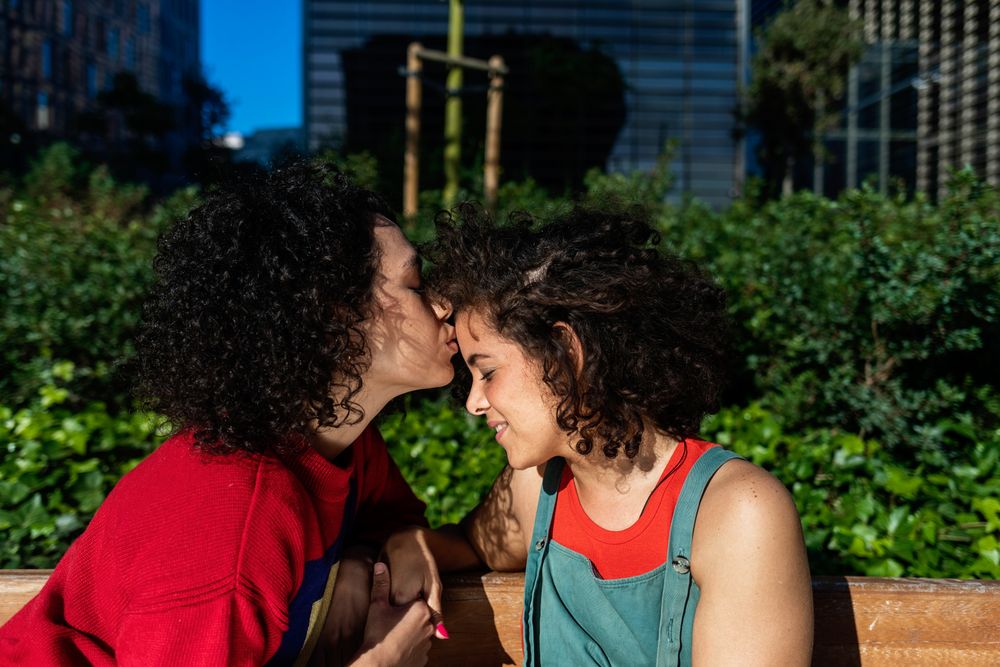 Happy female couple being affectionate in public park
