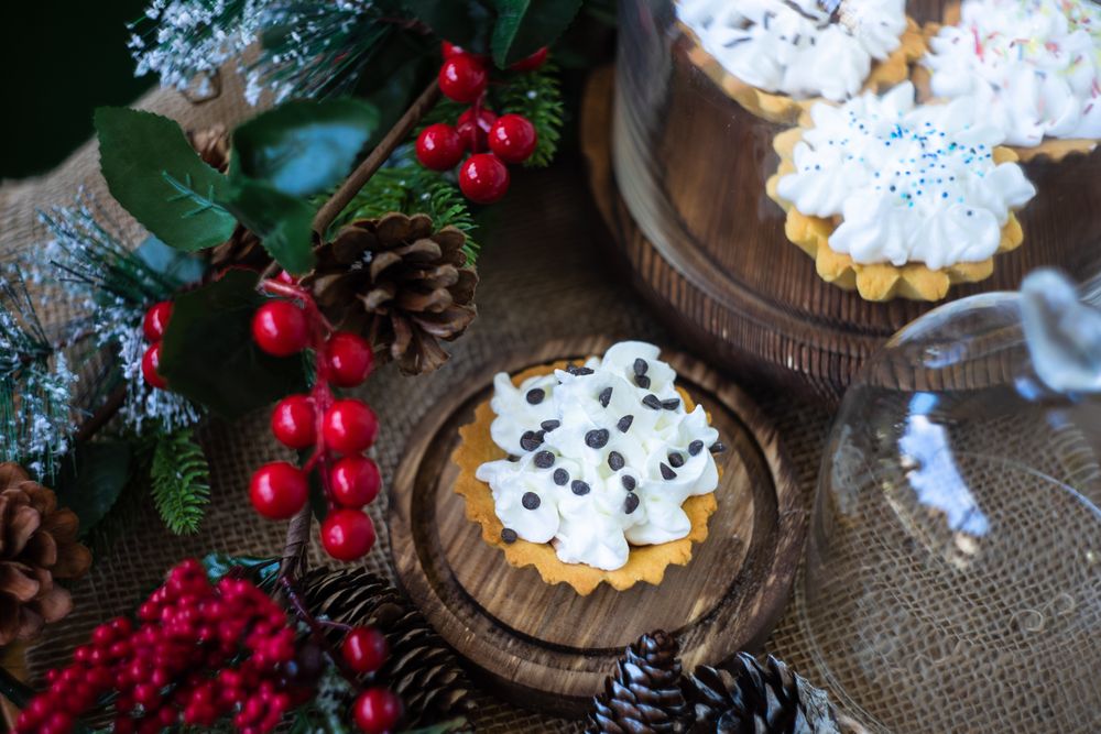 Top view of dessert pastries stuffed with cream and chocolate surrounded by holly