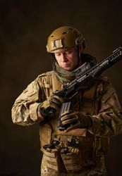 Young male military soldier reloads automatic airsoft rifle with telescopic sight