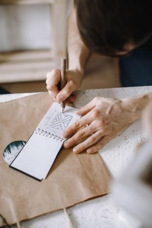 Man drawing a patterns on small notebook of paper