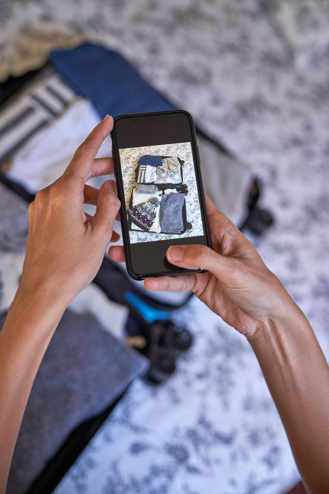 Crop traveler taking photo of opened suitcase