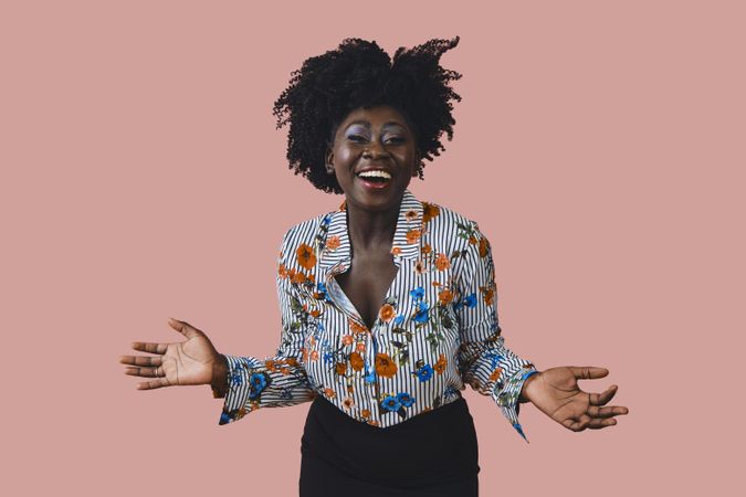 Portrait of smiling Black woman with her arms open next to her body