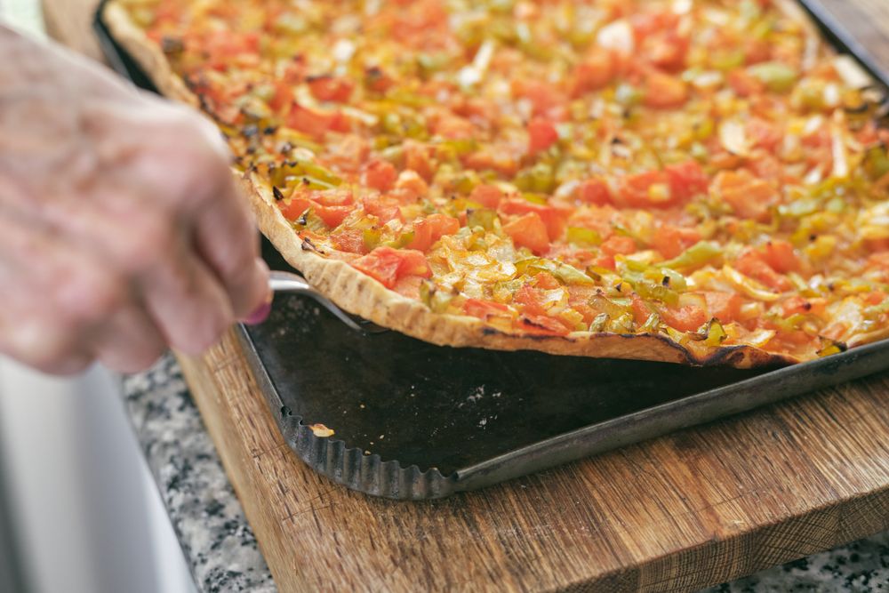 Crop woman serving delicious pizza on wooden board