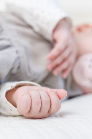 Hands closeup of baby girl sleeping over bedcover