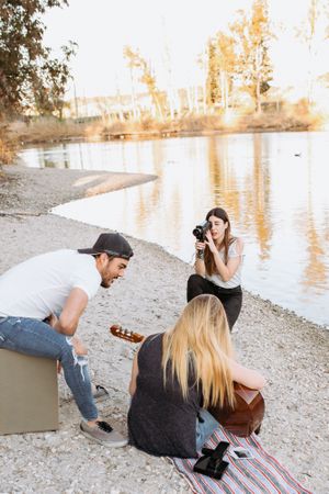 Young woman shooting friend playing guitar