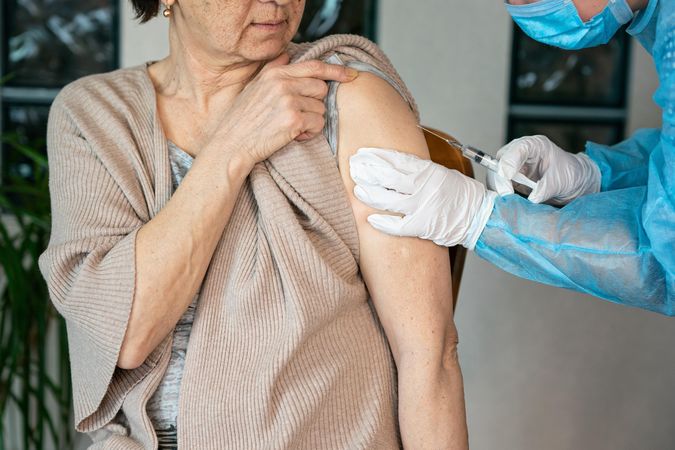 Healthcare worker injecting coronavirus vaccine into an older woman